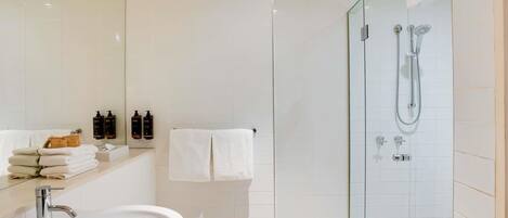 A modern bathroom with a sink, mirror, and glass-enclosed shower.