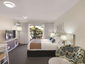 Relax in this cozy retreat with a large bed, flat-screen TV, and balcony overlooking palm trees.