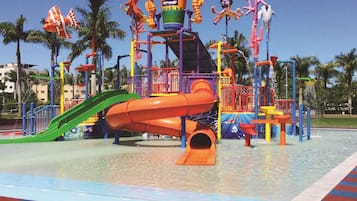 Enjoy the vibrant water park play area with a large water slide, water jets, and colorful play equipment.