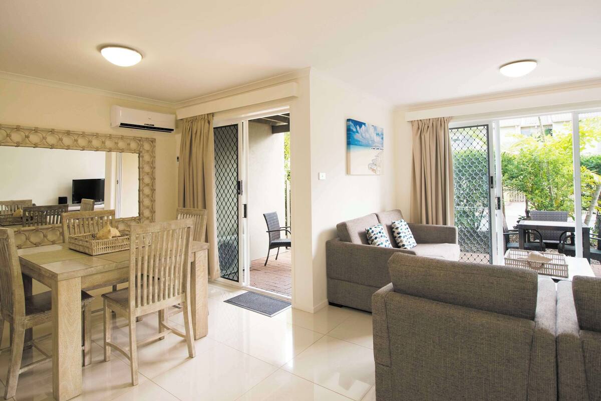 A spacious living area with a dining table, chairs, a sofa, and a TV.