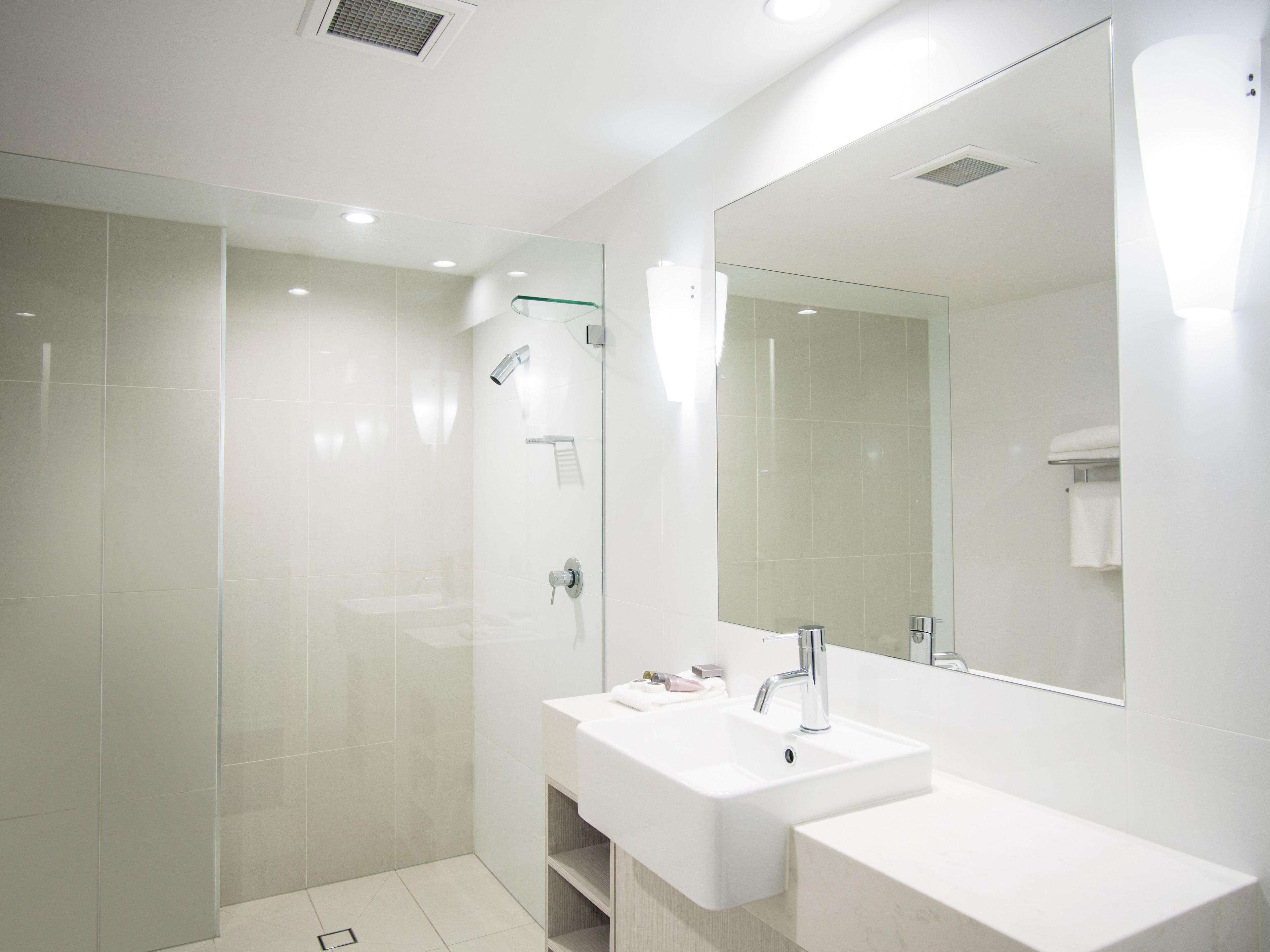 Une salle de bain moderne avec une douche à parois de verre, un lavabo blanc et un grand miroir.