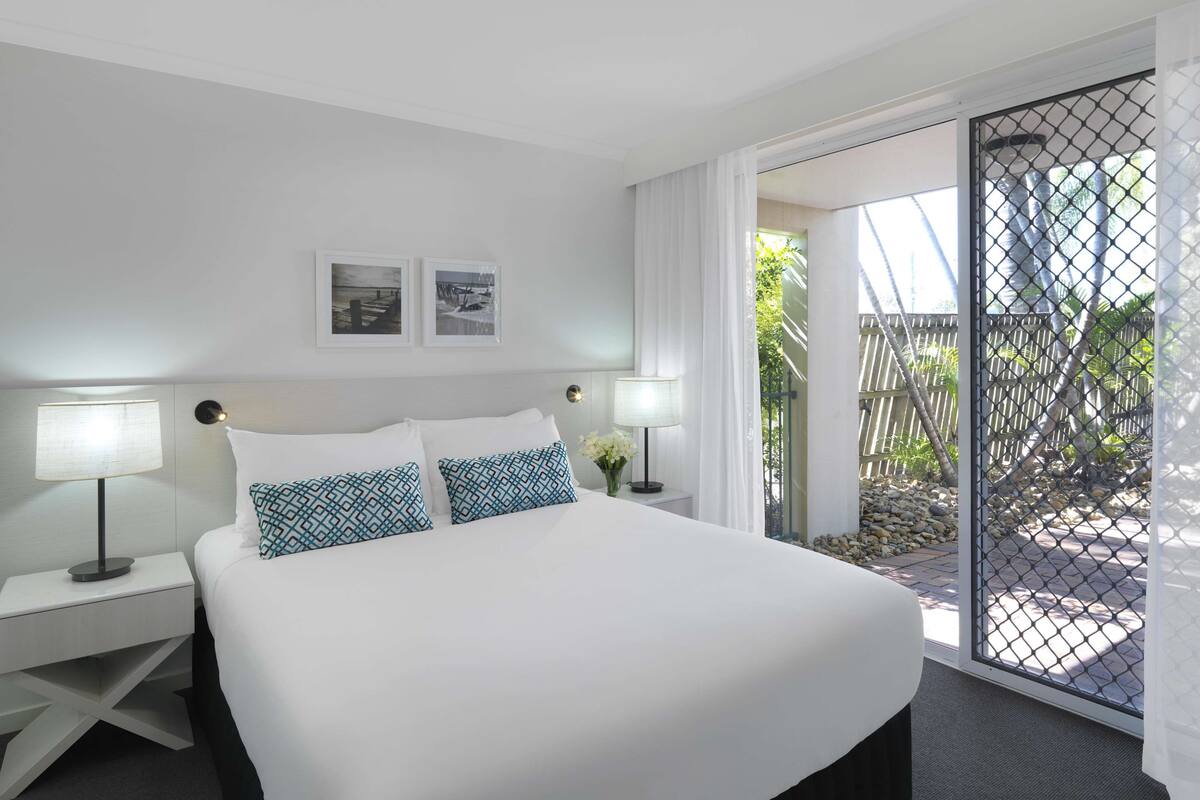 A hotel room with a large bed, two bedside tables with lamps, a ceiling light, and two framed pictures on the wall.