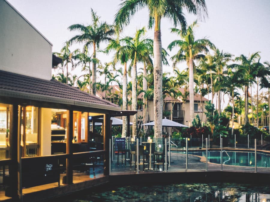 A poolside area with a bar, lounge chairs, and palm trees.