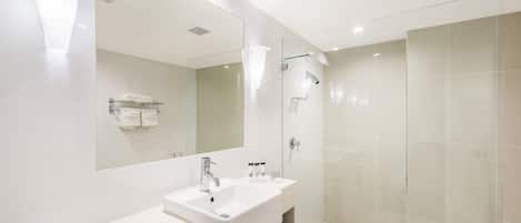 Une salle de bain moderne avec un grand miroir, deux lavabos, une douche et un porte-serviettes.