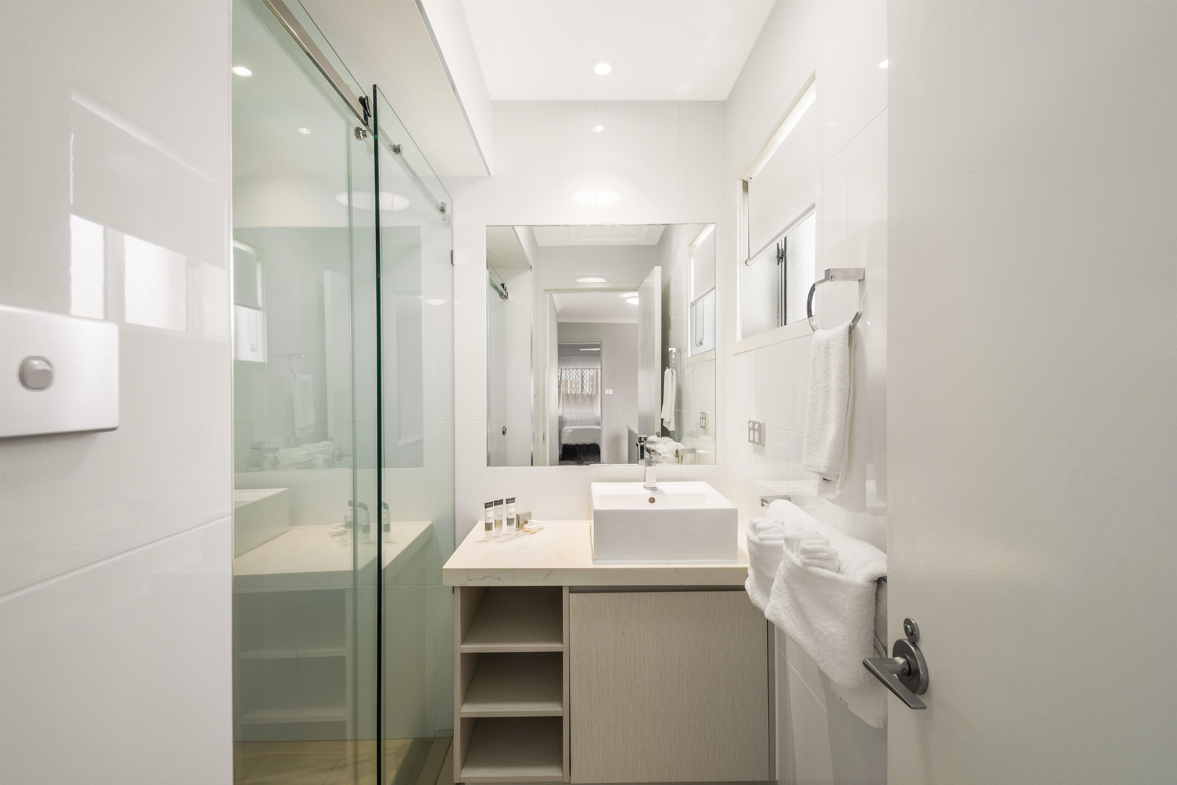 Une salle de bain moderne avec une douche à parois de verre, un meuble-lavabo et un porte-serviettes.