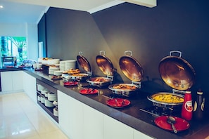 A buffet setup with various food items in metal serving dishes, arranged on a counter with a dark backsplash. - Oaks Sunshine Coast Oasis Resort (Golden Beach)