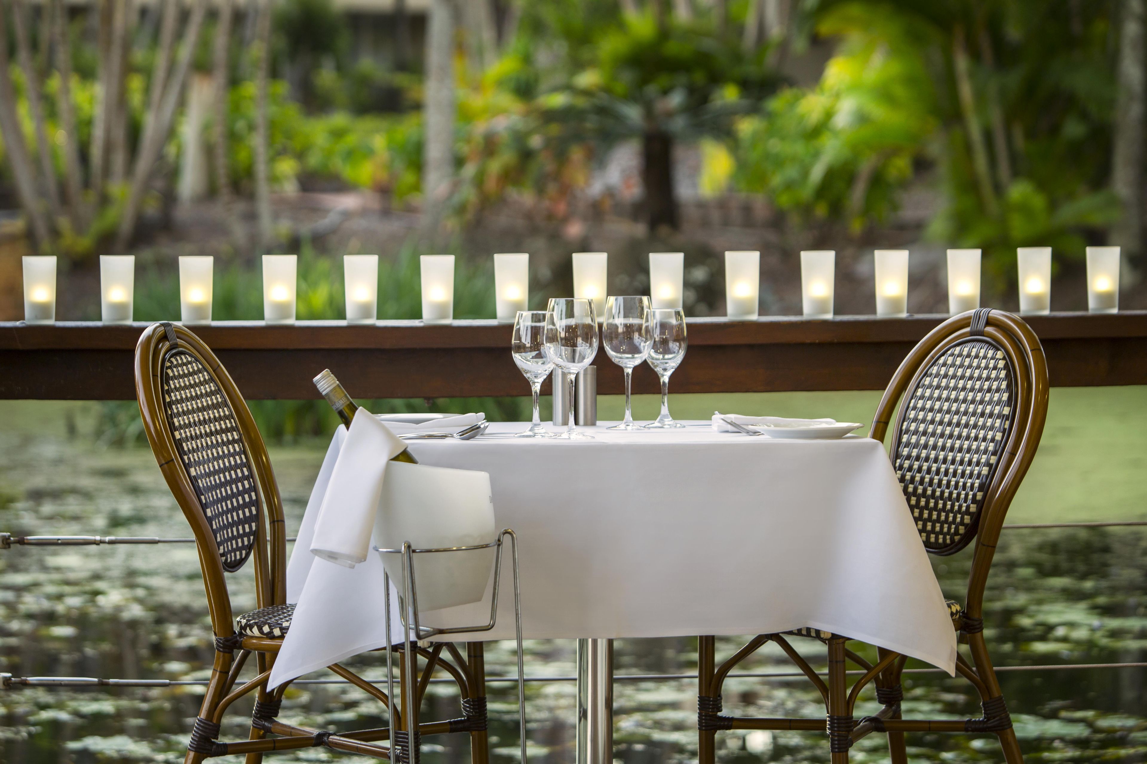 A table set for dining with chairs, candles, and a bottle of wine.