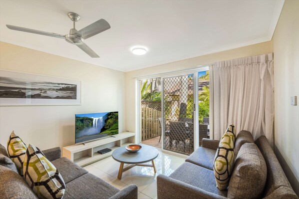 Relax in this stylish living room with a flat-screen TV, comfortable sofa, and a beautiful garden view.