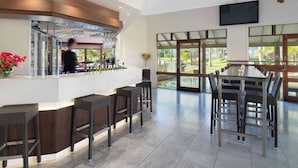 A modern bar area with a counter, bar stools, and a television mounted on the wall.