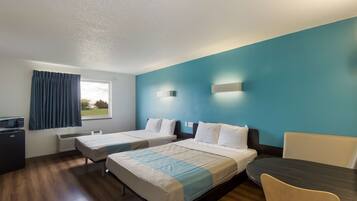 Habitación de hotel con dos camas, un escritorio, una silla, un televisor y una ventana con cortinas.