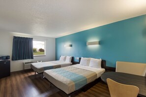 A hotel room with two beds, a desk, a chair, a TV, and a window with curtains.