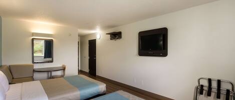 A hotel room with two beds, a desk, a chair, a TV, and a window with curtains.
