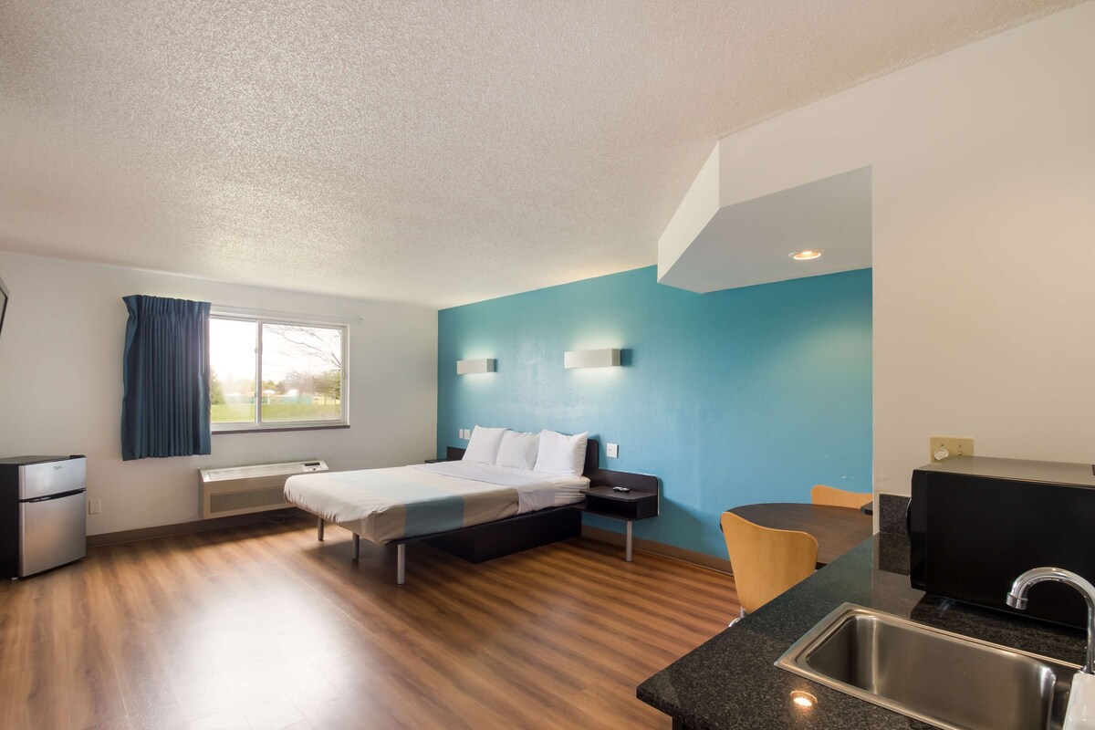 Une chambre d’hôtel moderne équipée d’un lit, d’un bureau, d’un lavabo et d’une fenêtre avec des rideaux.