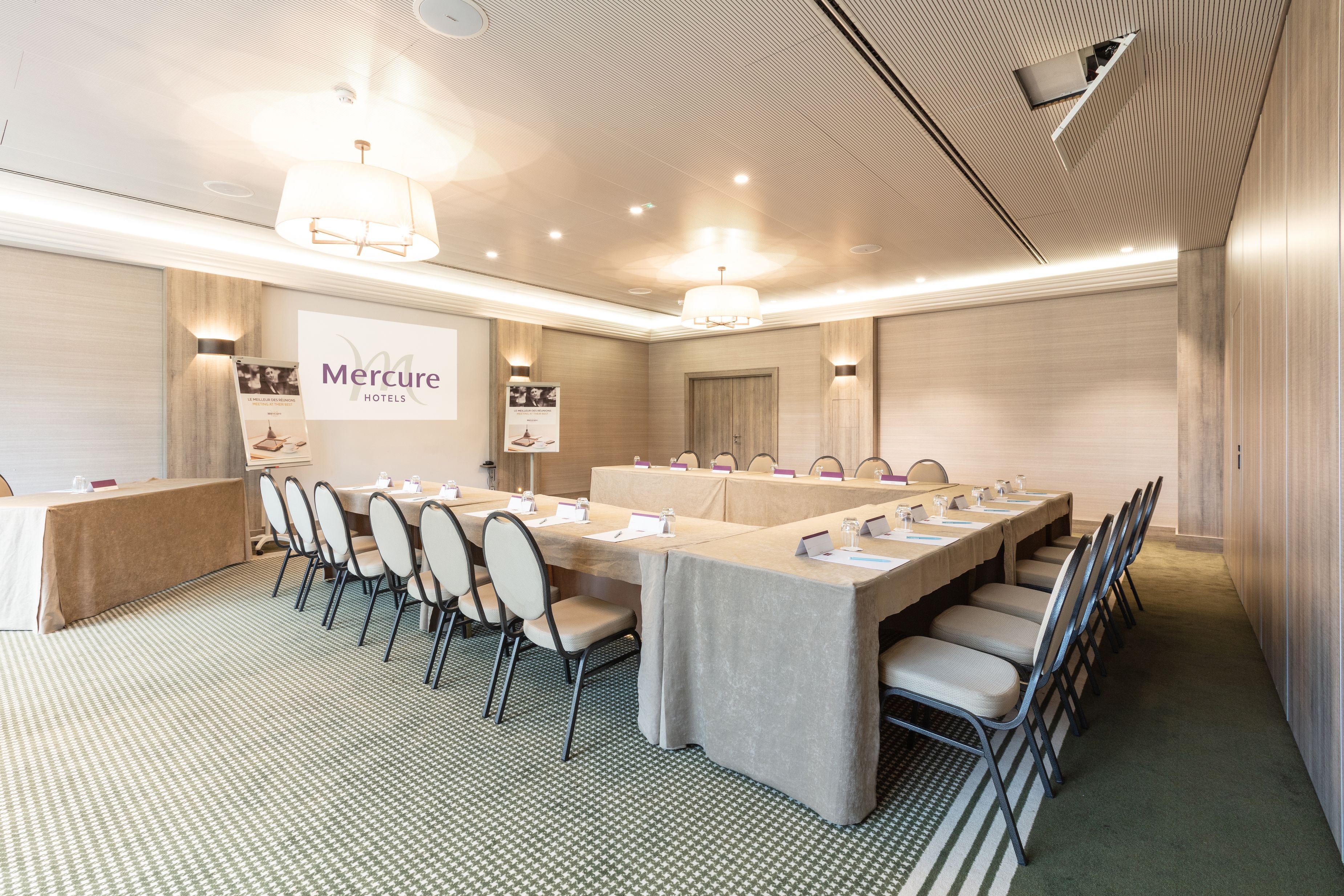 Une salle de conférence avec une longue table, des chaises et une banderole sur laquelle on peut lire « Hôtels Mercure ».