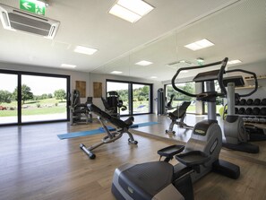 Una palestra con attrezzature per esercizi, ampie finestre e vista sull'esterno.