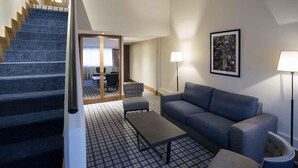 Une chambre d’hôtel avec un escalier, un canapé, une table basse, une lampe et un tableau au mur.