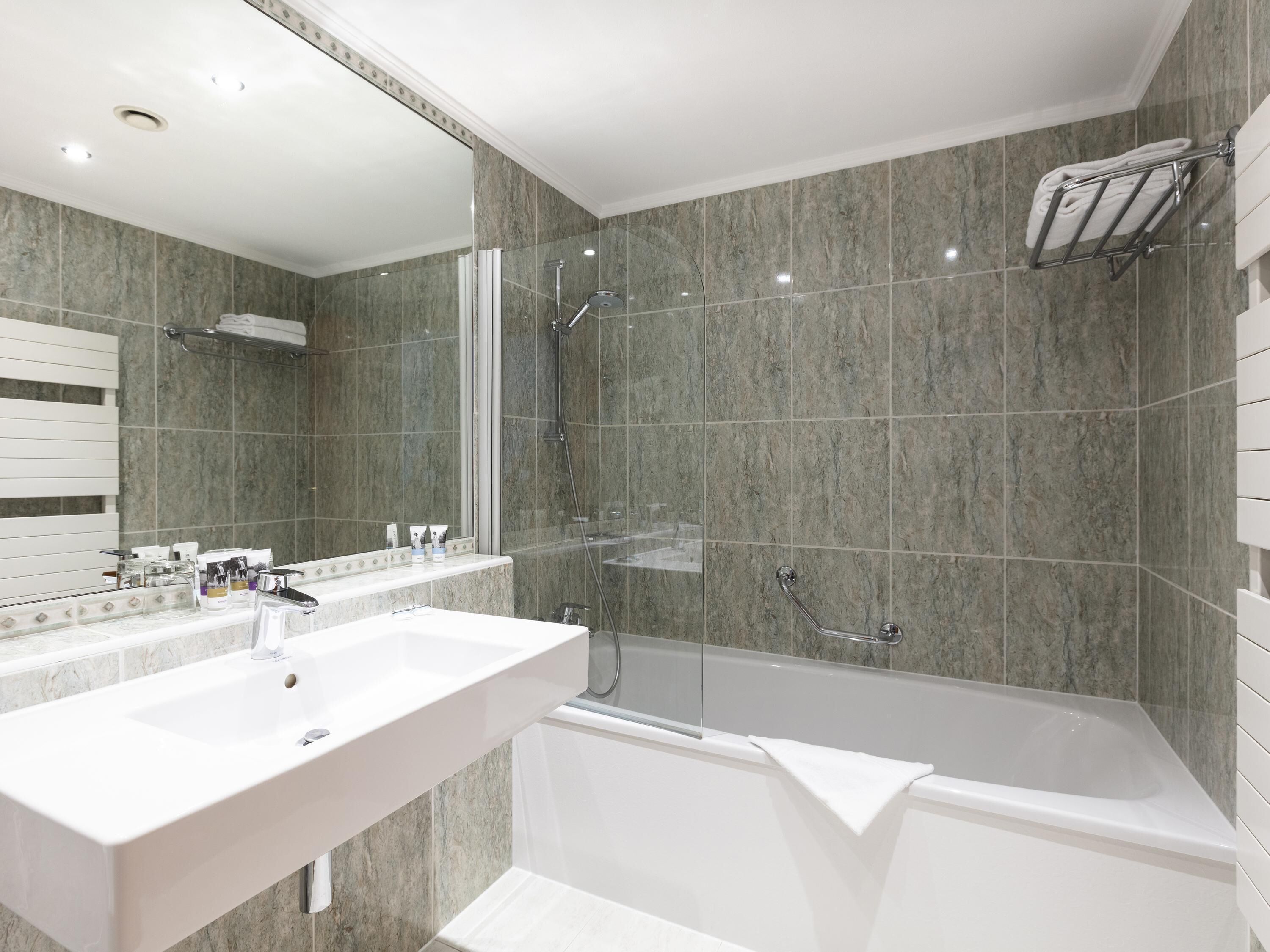 A modern bathroom with two sinks, a glass-enclosed shower, and a bathtub.