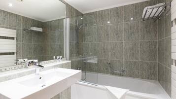 A modern bathroom with two sinks, a glass-enclosed shower, and a bathtub.