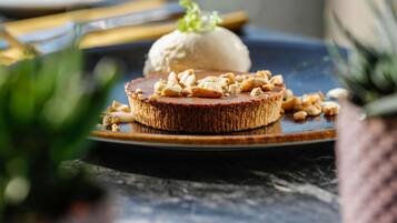 Un plato de postre con una rebanada de pastel cubierta de nueces y una bola de helado.