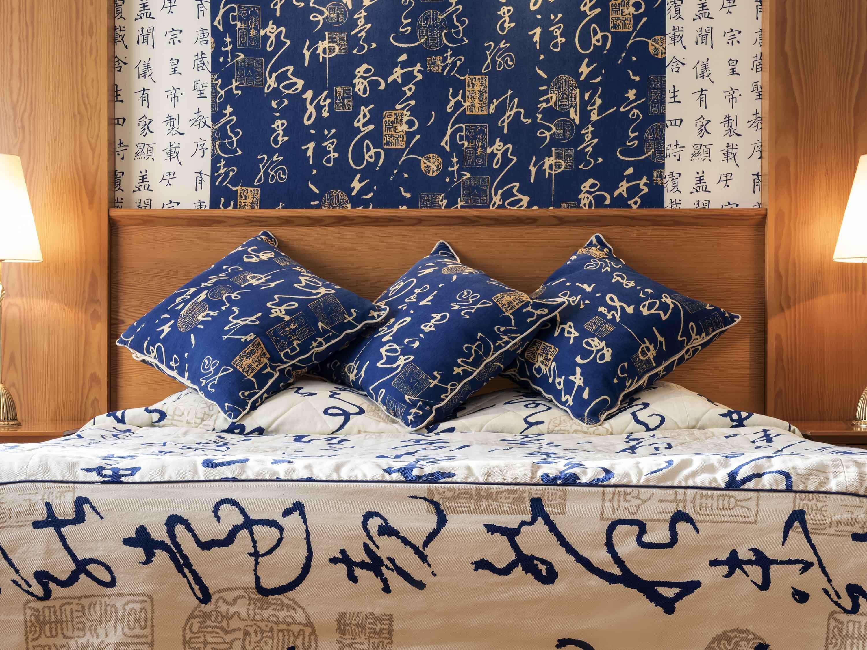 A bed with blue and white bedding, two blue pillows, and a wooden headboard.