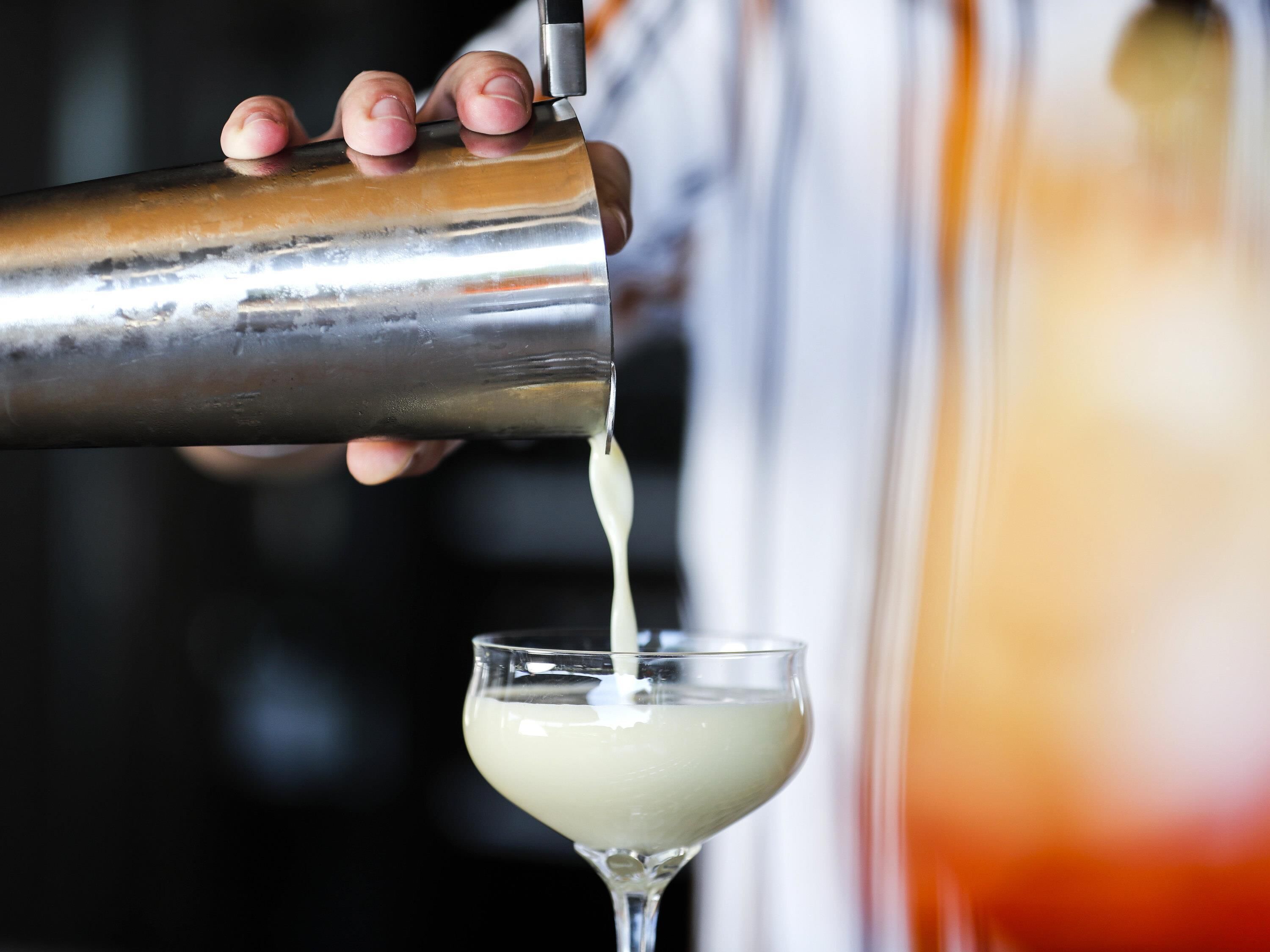 Une personne verse une boisson d’un shaker dans un verre.