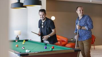 A pool table with balls, a lamp, and a person playing.