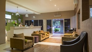 Un'area della reception di un hotel con scrivania, diversi divani e poltrone disposte per gli ospiti.