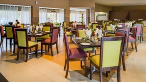 Un'ampia sala da pranzo con diversi tavoli e sedie, ogni tavolo apparecchiato con piatti, posate e tovaglioli.