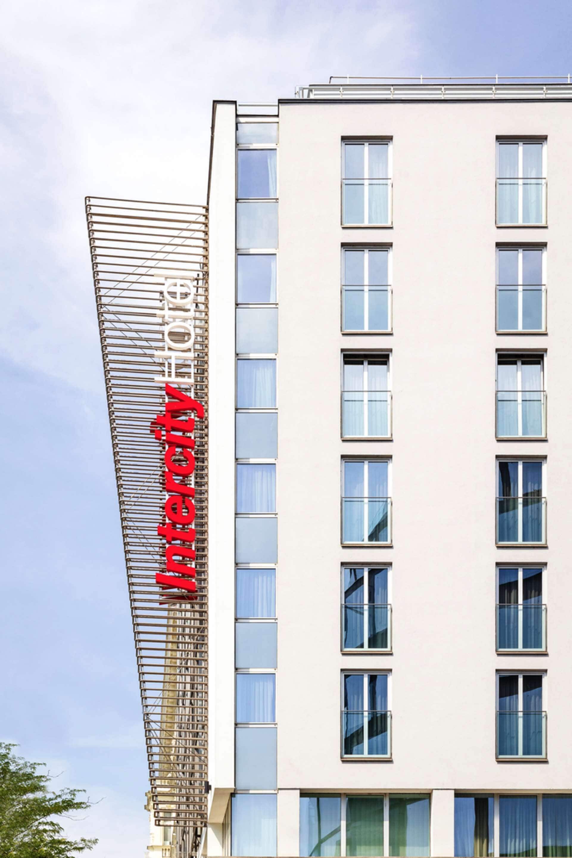 Un moderno edificio de hotel con un llamativo letrero vertical que muestra el nombre "HOTEL CITY".