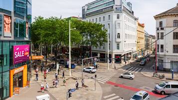 Eine belebte Stadtstraße mit Fußgängern, Autos und einer Fußgängerampel.
