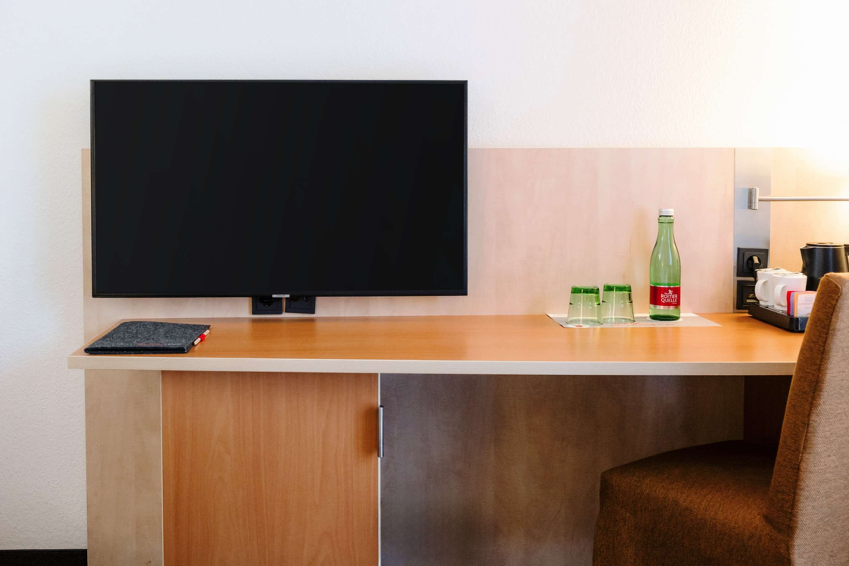 Ein Hotelrezeptionstresen mit Fernseher, Notizbuch und einer Coca-Cola-Flasche.