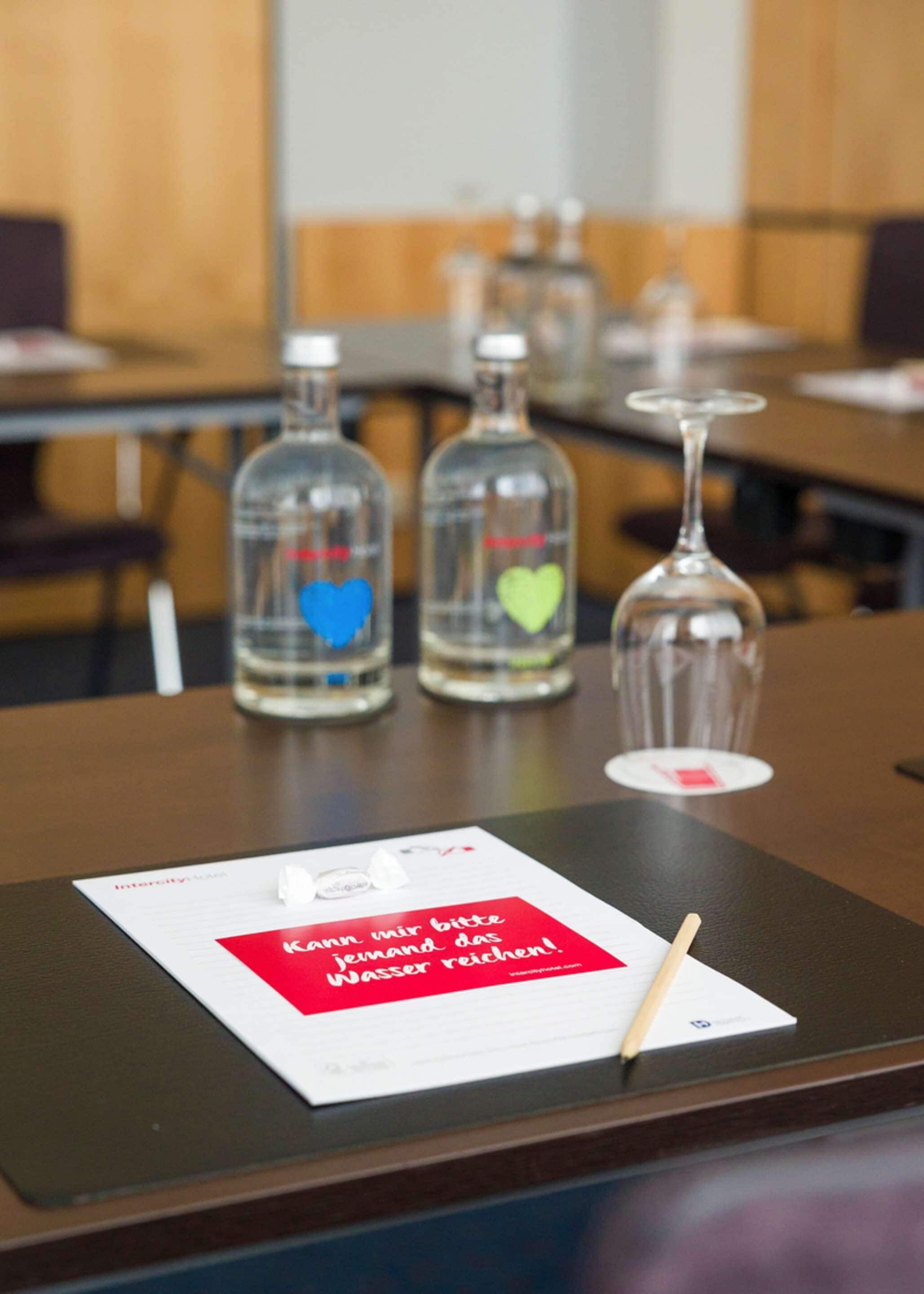 A table with three bottles and a wine glass, a menu, and a red sign with white text.
