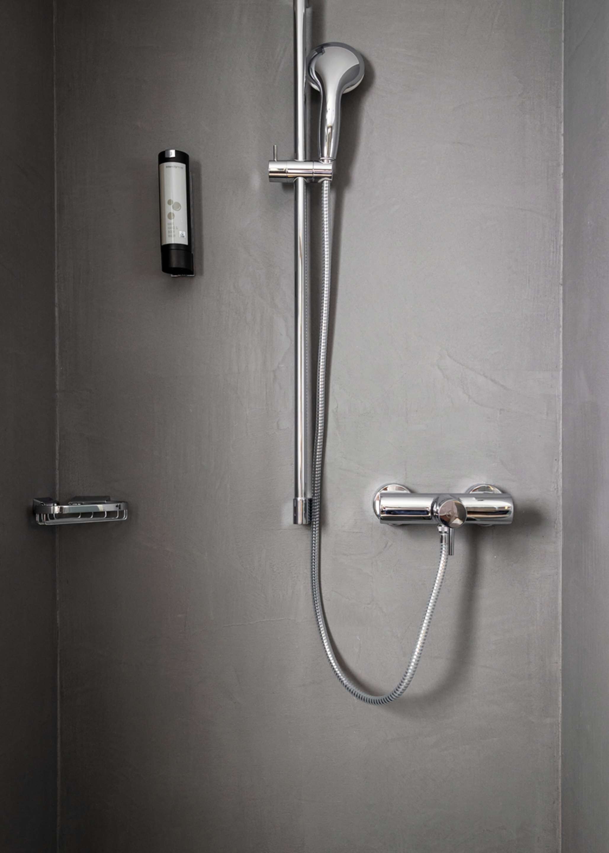 A modern bathroom with a shower, a soap dispenser, and a towel rack.