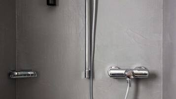 A modern bathroom with a shower, a soap dispenser, and a towel rack.