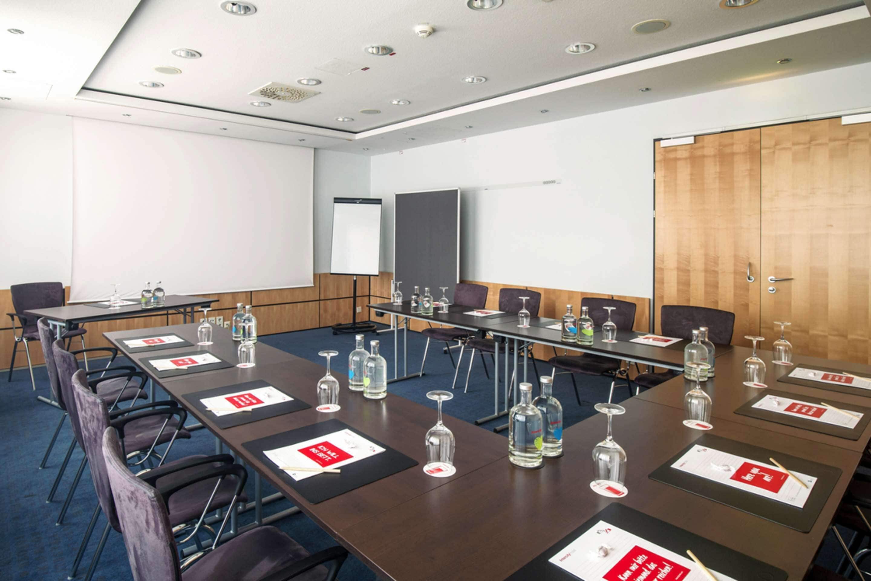 Une salle de conférence équipée d’une longue table, de chaises et d’un écran de projection.