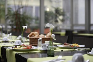 Una mesa con desayuno: cruasanes, huevos y un pequeño florero.