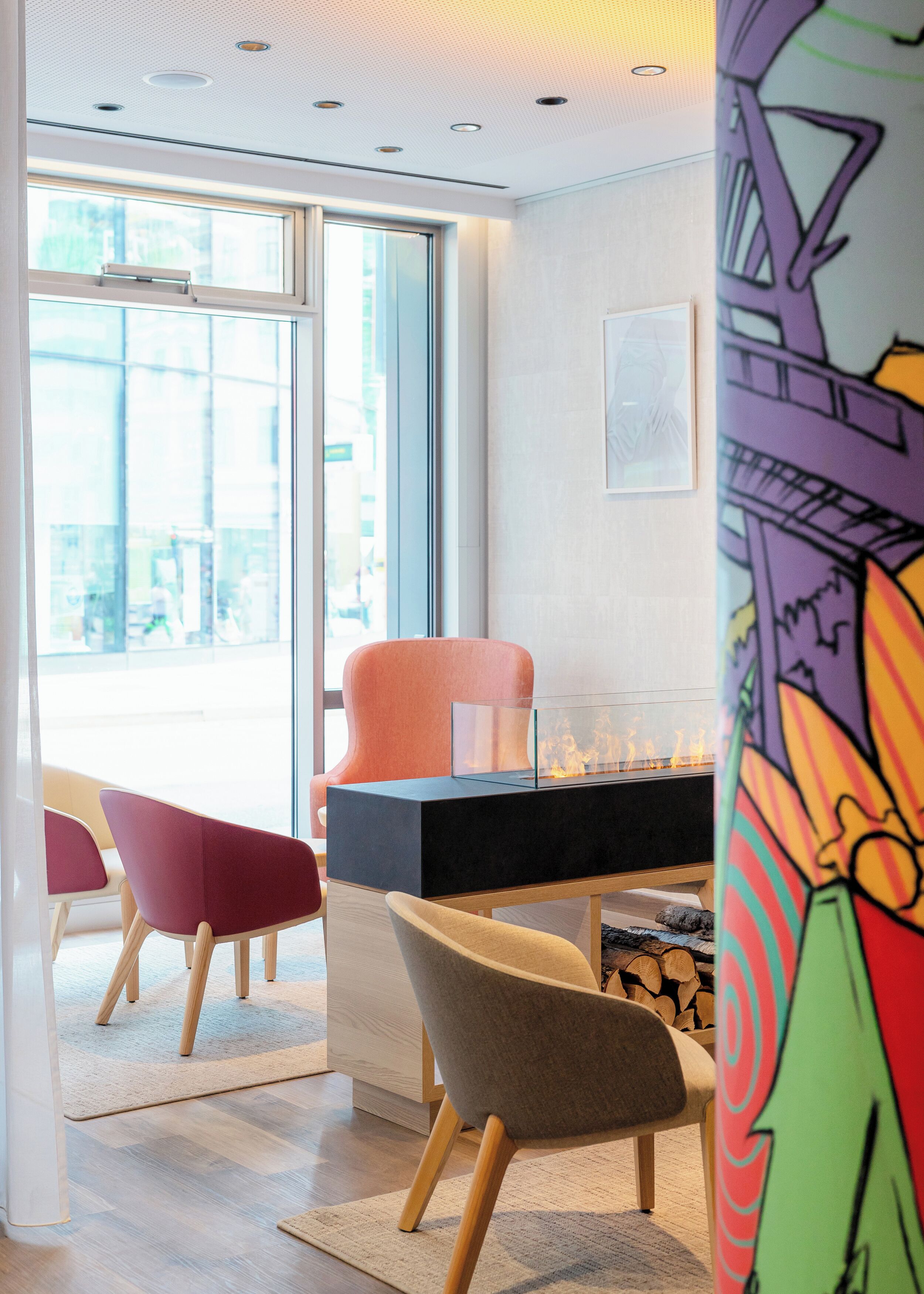 Un intérieur moderne avec une table à plateau de verre, des chaises colorées et une cheminée.