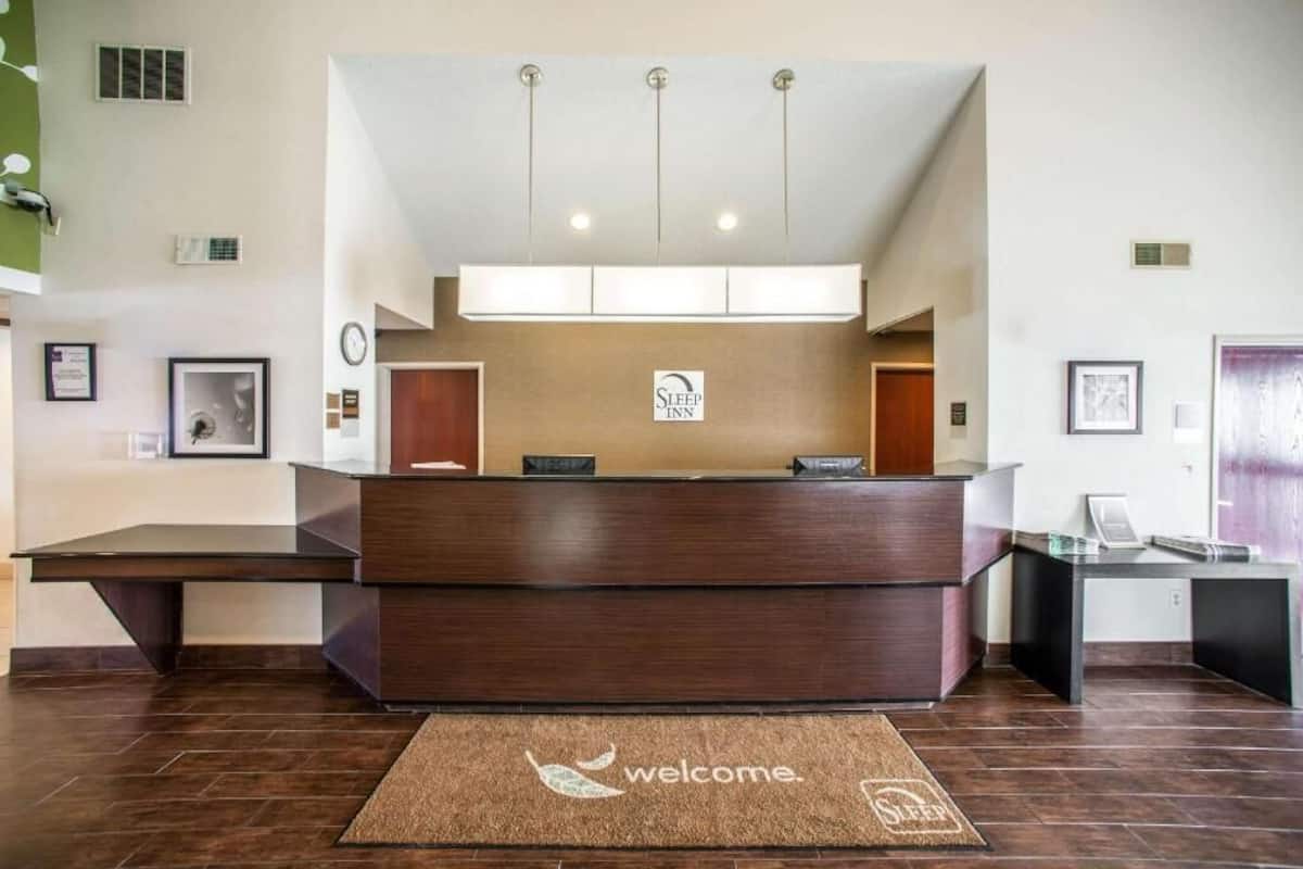 A reception desk with a 'Welcome' mat, a clock, and a sign indicating 'Sleep Inn.'