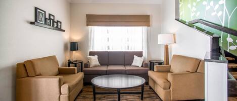 A living room with a sofa, two armchairs, a coffee table, and a patterned rug.
