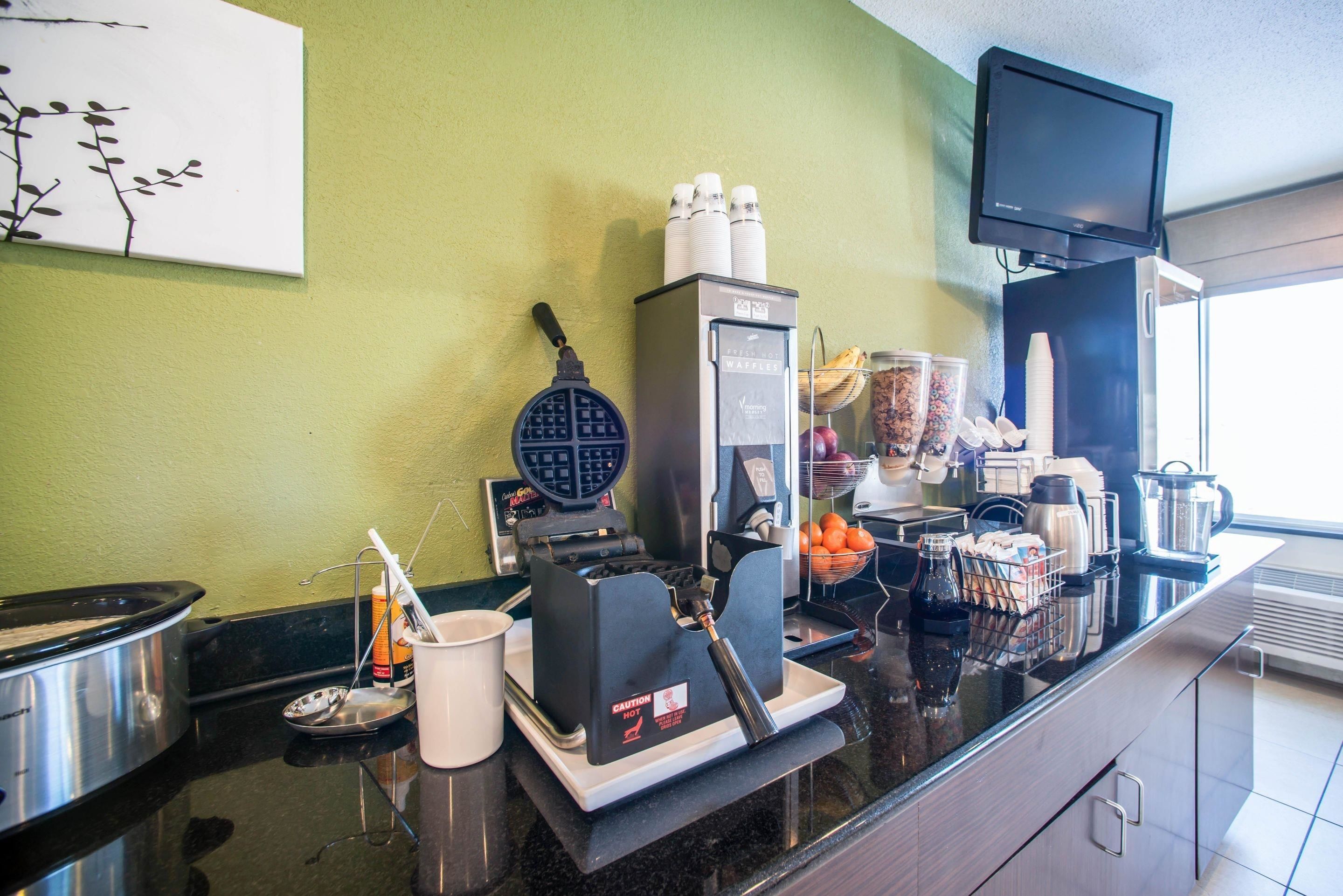 A kitchen with a waffle maker, coffee machine, and various kitchen appliances.