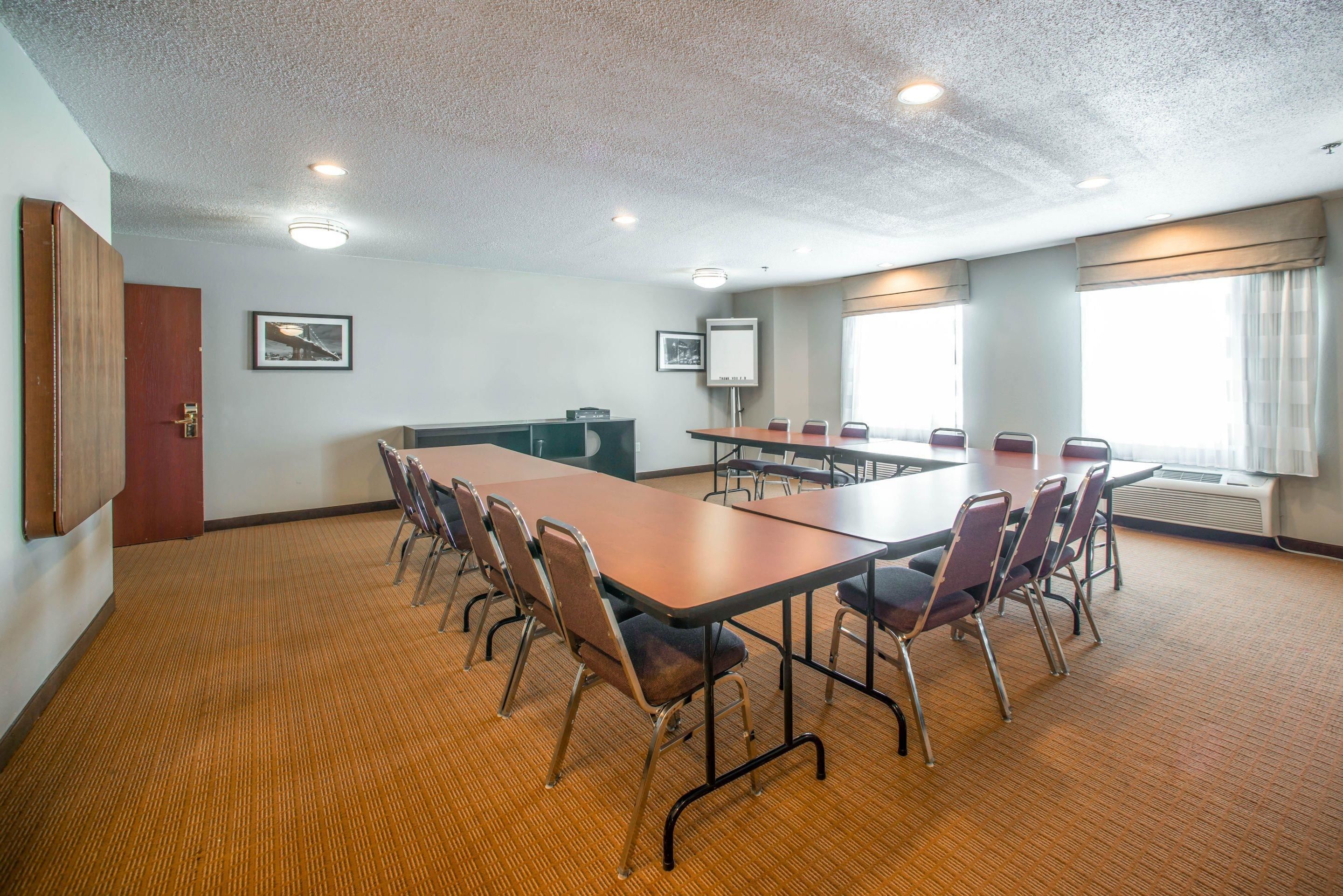 Una sala conferenze con un lungo tavolo, sedie, un proiettore e una lavagna.