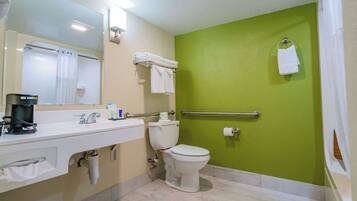 Une salle de bain avec un lavabo blanc, des toilettes et un mur vert.