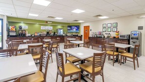 Un restaurante con varias mesas y sillas, una zona de cocina y un cajero automático.