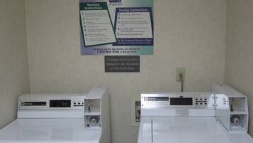 Two front-loading washing machines with instruction posters on the wall.