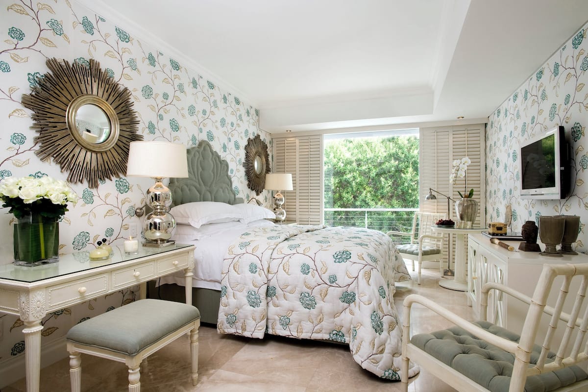 A bedroom with a bed, a vanity, a desk, and a chair.