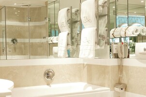 A modern bathroom with a glass-enclosed shower, a large mirror, and neatly folded towels with monogrammed towels on a rack.