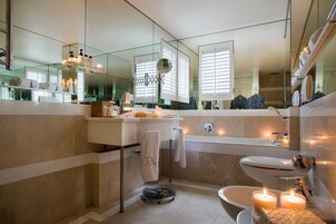 A modern bathroom with a large mirror, a sink, a toilet, and a bathtub.