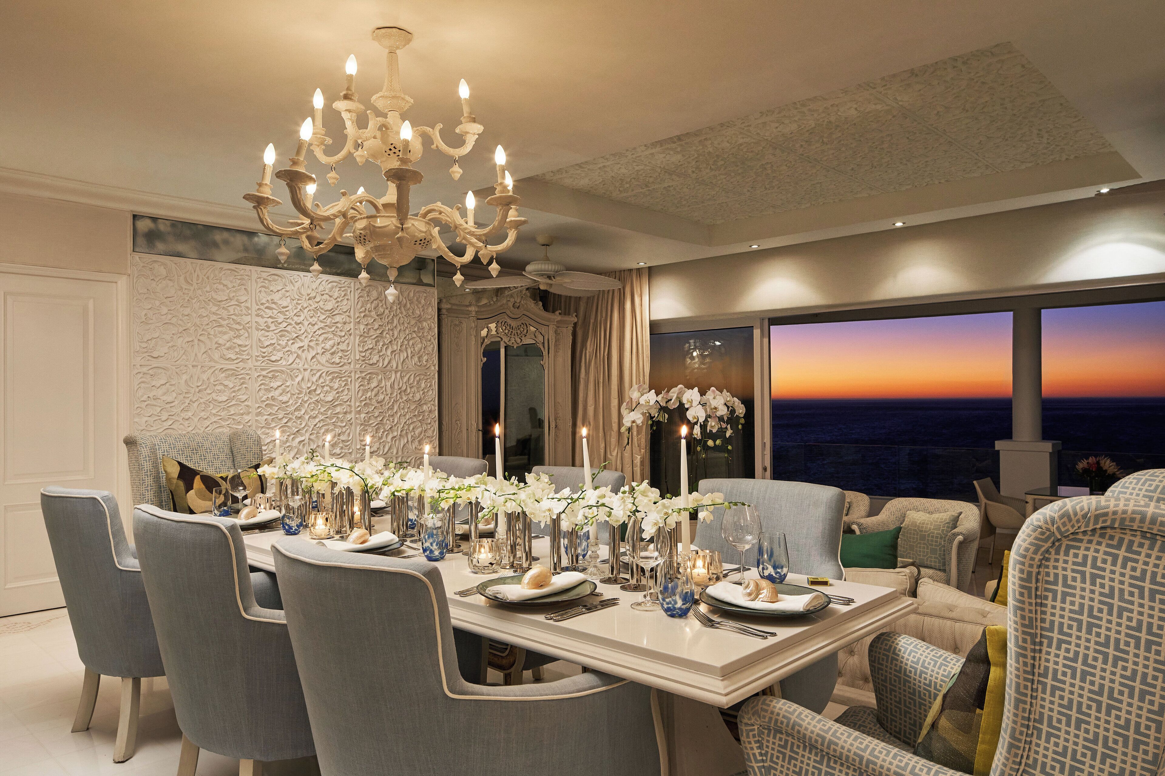 A dining area with a chandelier, ornate wall paneling, and a view of the sunset.
