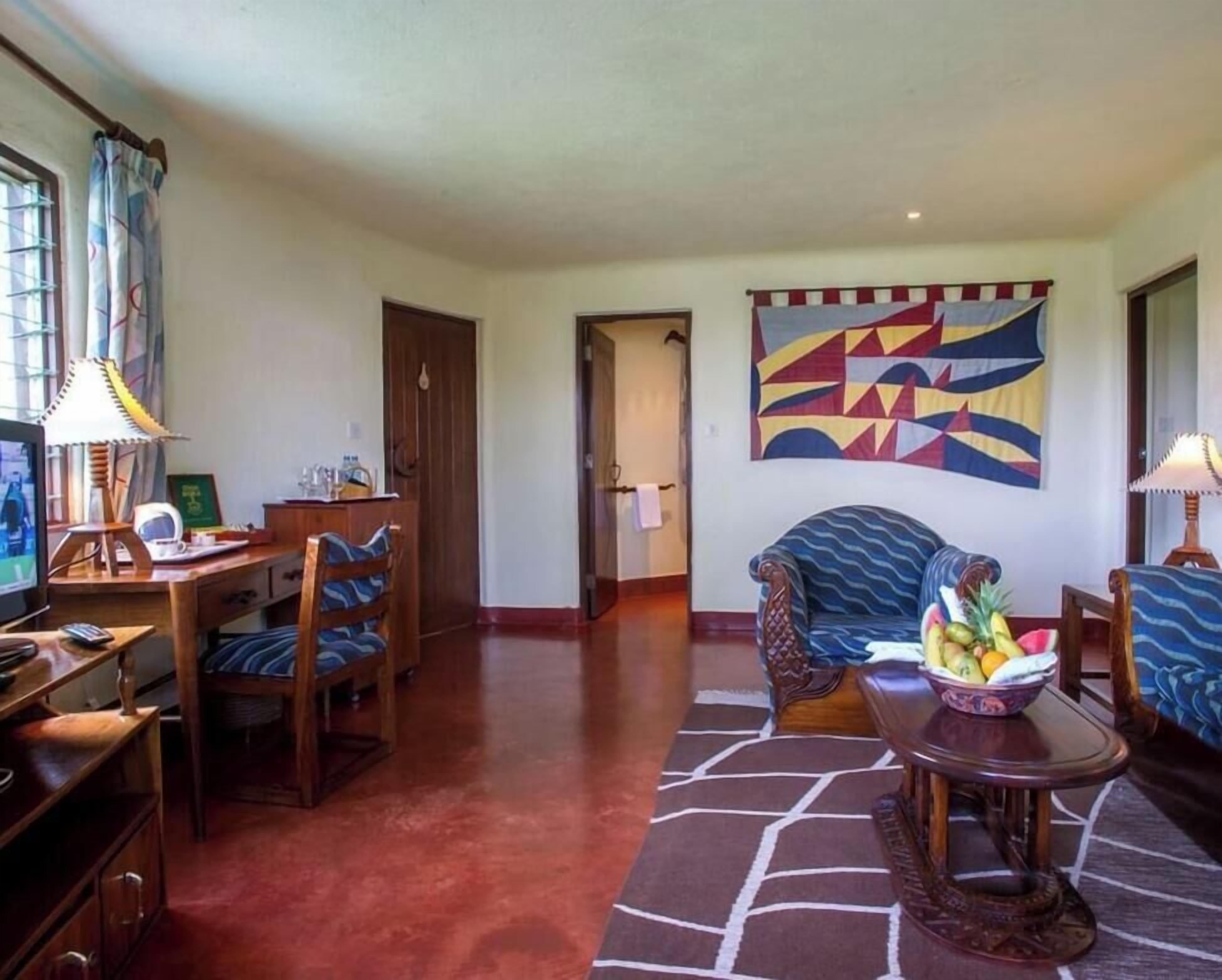 Una sala de estar con televisor, una mesa de comedor, sillas, un sofá y un cuadro abstracto de colores en la pared.