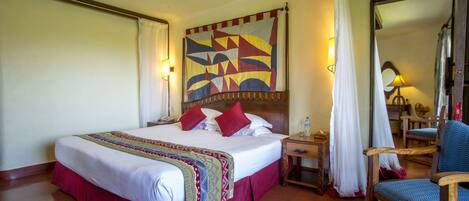 Une chambre d’hôtel avec un grand lit, une tête de lit en bois, une table de chevet, une chaise et un miroir.